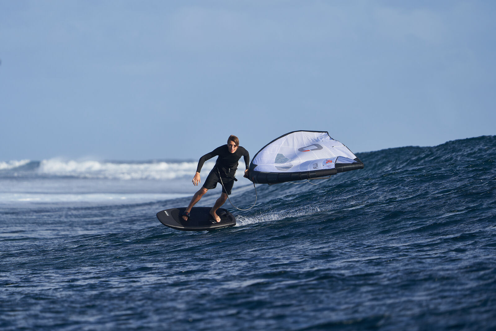Guy winging on a wave with ozone flux wing and Rise wing board 