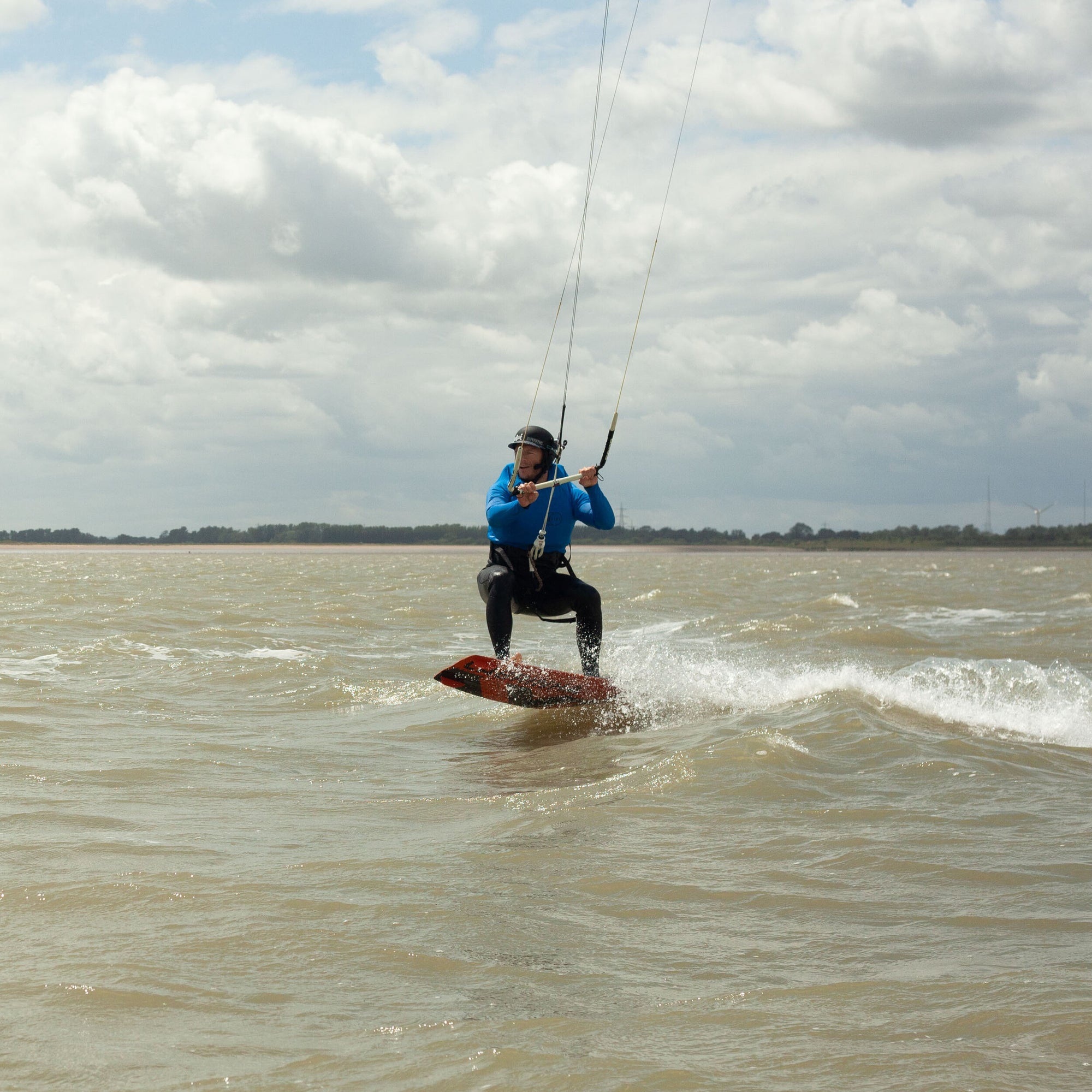 Tide Watersports private kitesurfing lesson in progress with the student using a bb talking bluetooth headset to talk to the instructor so that they get direct feedback when learning. the student it riding cleanly upwind and having lots of fun.