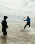 A tide Watersports kitesurfing instructor teaching a student using the bb talking Bluetooth headsets on a private kitesurfing lesson when teaching someone how to ride upwind.