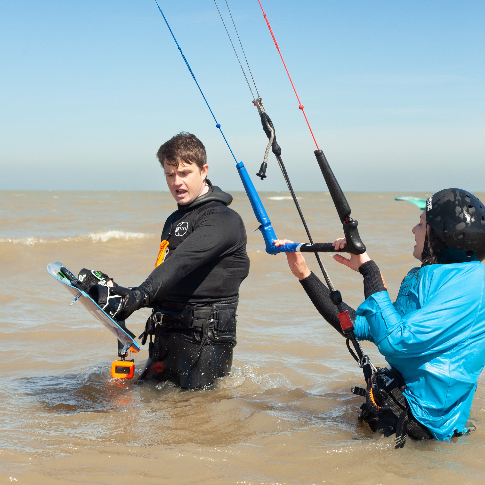 Tide Watersports private kitesurfing lesson in progress in Margate, Kent with the instructor showing the student a valuable lesson on how to hold the board when putting it on your feet in the water whilst holding a kite in the air.