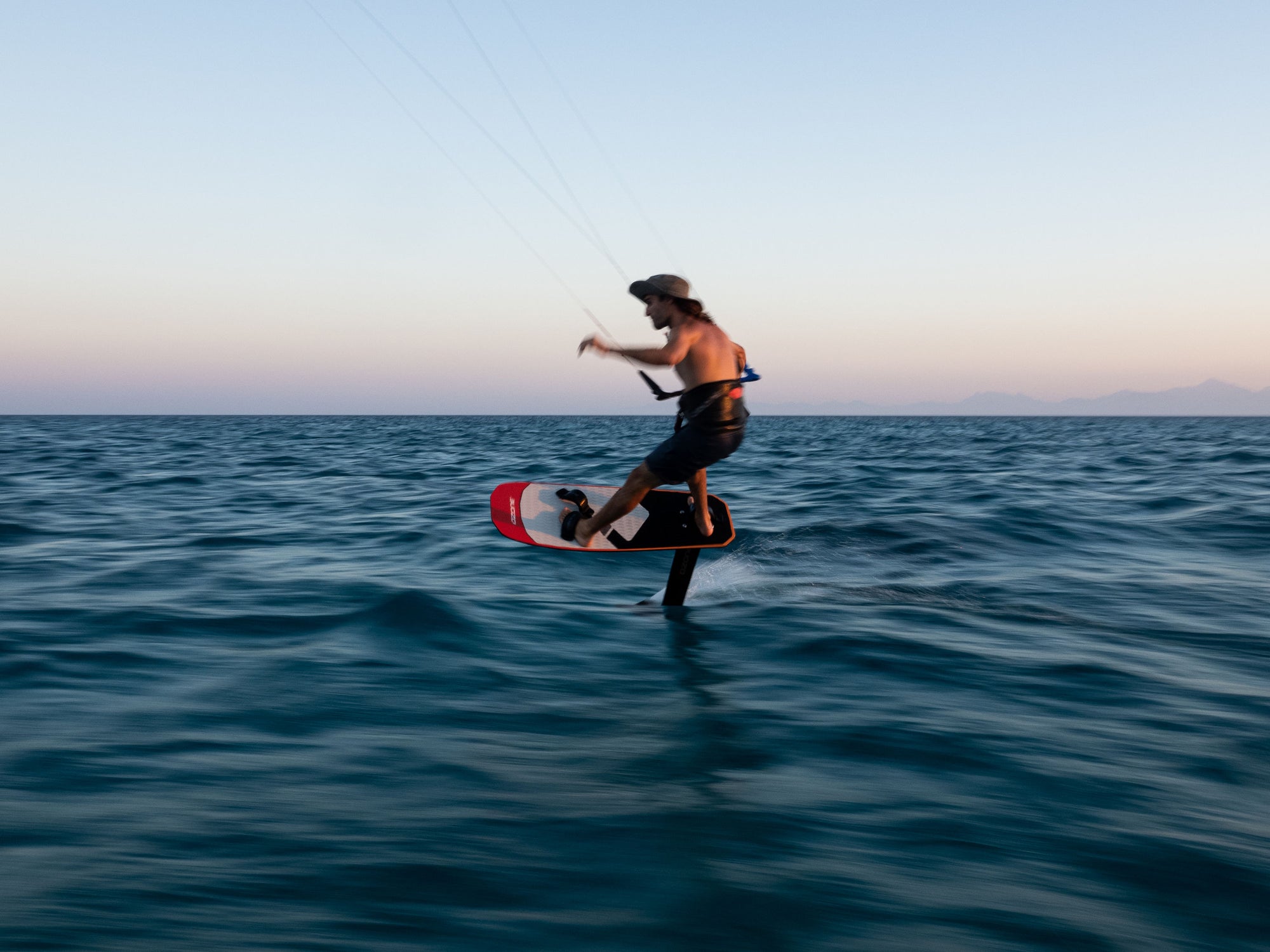 Kitesurfer foiling at sunset on the Ozone Apex V1 foil and board.