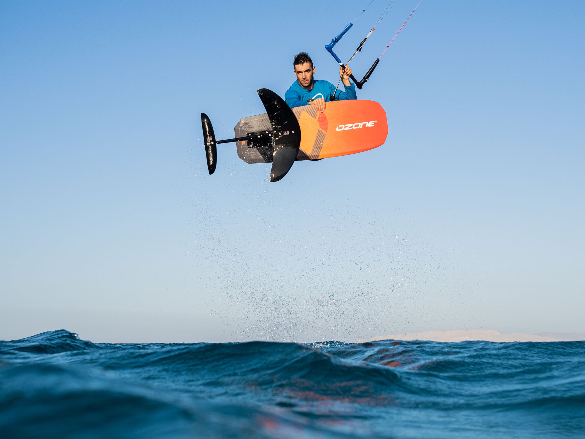 Ozone kitesurfer jumping through the air with the Ozone Apex V1 foil and board.
