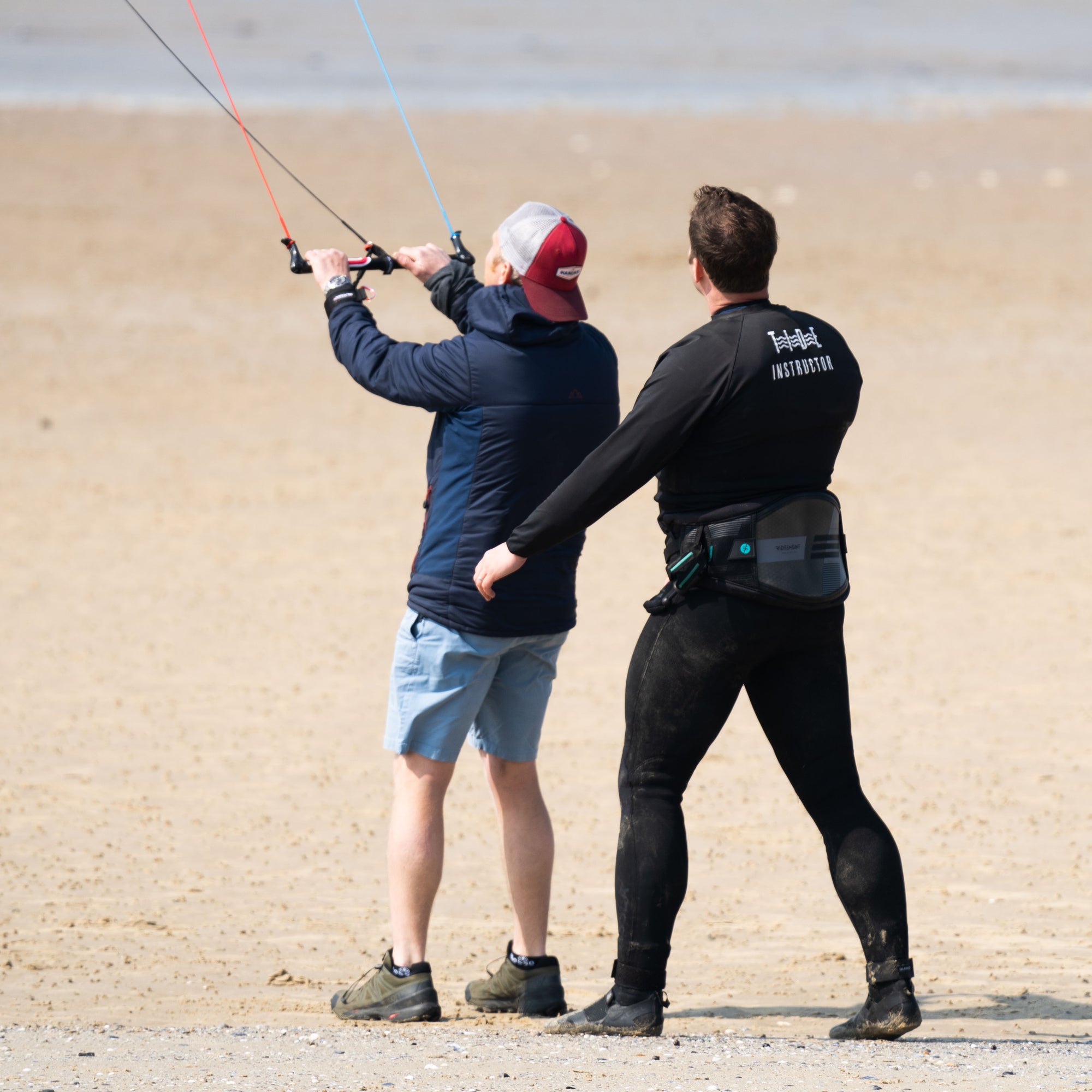 Kitesurfing instructor and student flying an Ozone Ignition trainer kite on the gold sand beach of Minnis Bay near Margate, Kent whilst on a Kitesurfing taster lesson.